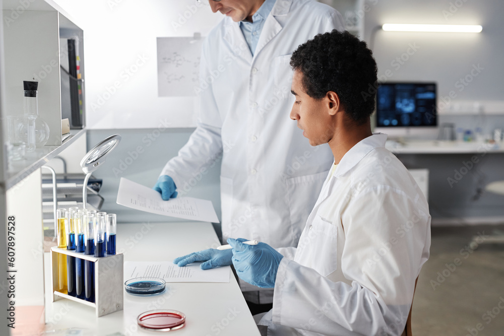 Side view portrait of two scientists working with documents in laboratory, copy space Side view portrait of two scientists working with documents in laboratory, copy space