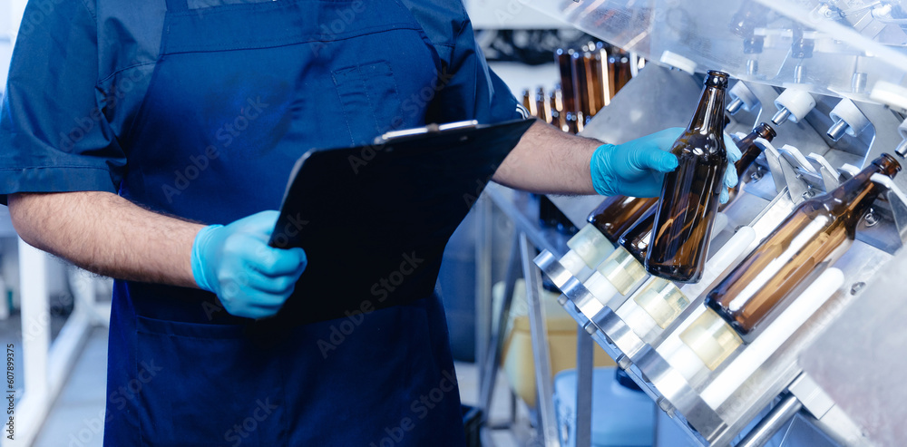 Worker man with tablet control drink production line with bottles beer in of brewery factory industry Worker man with tablet control drink production line with bottles beer in of brewery factory industry