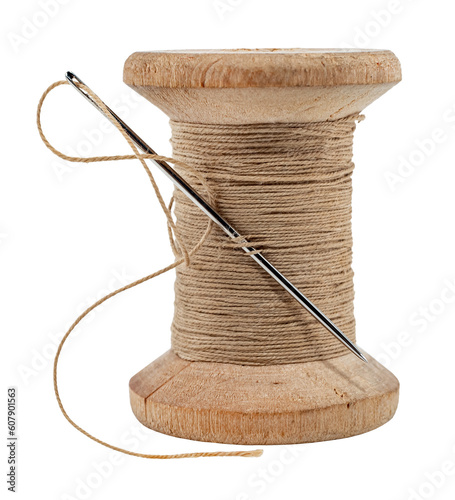 Old wooden spool of thread and needle on a white background. Sewing accessories