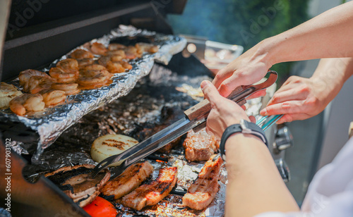 Barbecue grill with meat, shrimp, chicken, vegetables, and hand grilling food symbolizes festive outdoor cooking and celebration during a national holiday