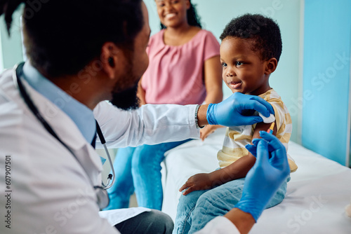 Smiling black boy receiving vaccine at pediatrician's office. photo