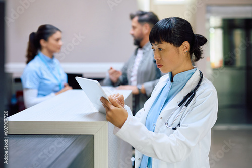 Japanese female doctor working on touchpad in hospital.