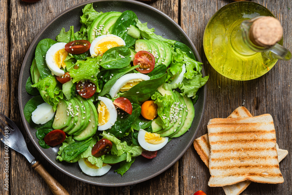 Salad with spinach, avocado, tomatoes in a plate. Vegetarian salad
