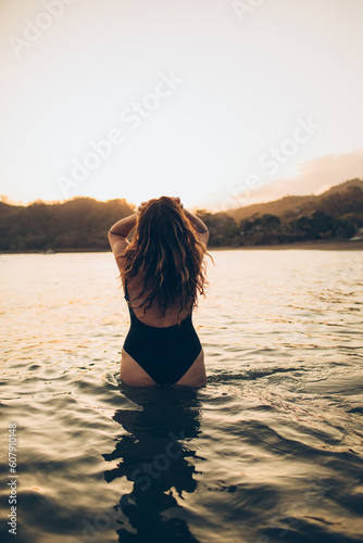 woman standing in the water looking at the sunset on the beach