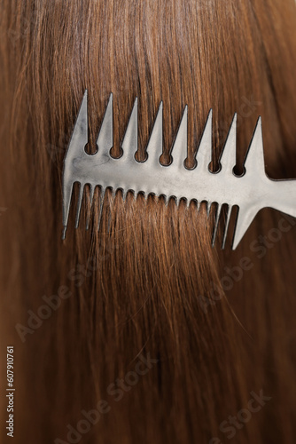 Close up of haircare, comb moves along beautiful healthy long flowing brown hair, texture. Healthy long smooth flowing brown hair