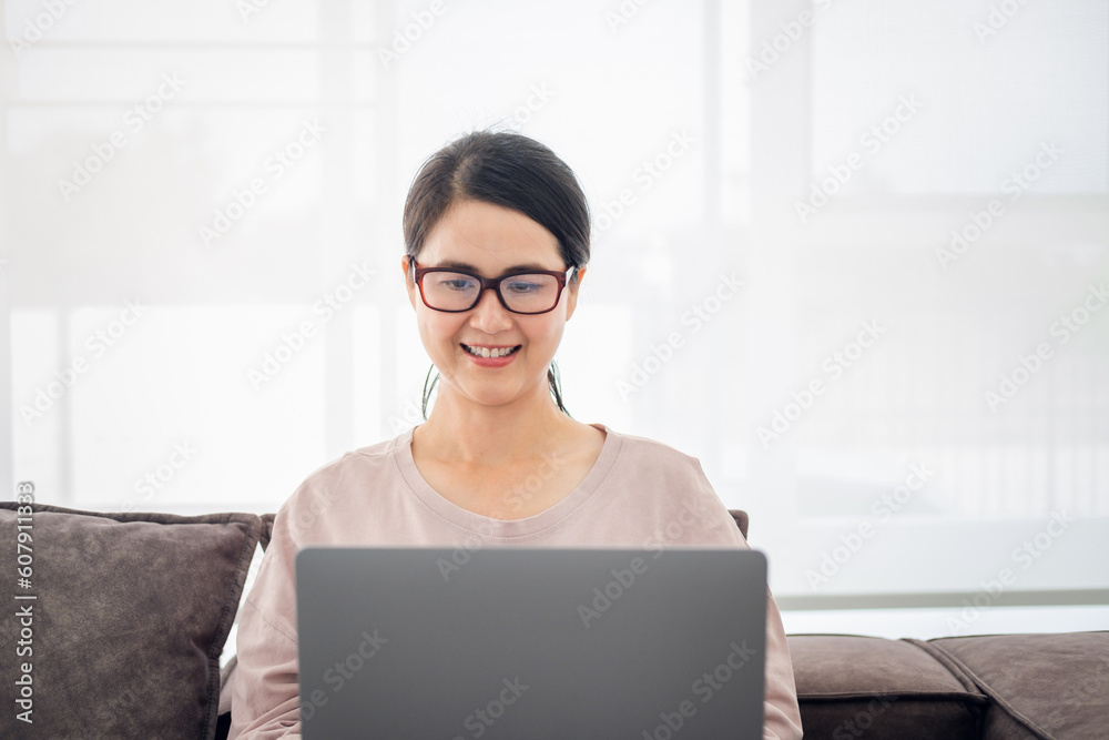 Home office. Confident senior business woman working with laptop on sofa couch in living room at home, free space Home office. Confident senior business woman working with laptop on sofa couch in living room at home, free space