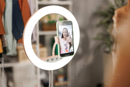 Beauty influencer filming tutorial at home. Female blogger live streaming a broadcast online with ring light for a vlog channel. Recording fun podcast for followers on social media