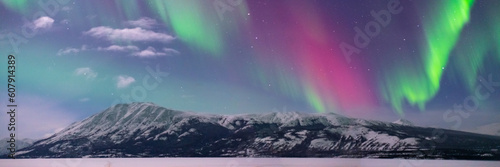 Panoramic landscape aurora borealis views in northern Canada, Yukon Territory during winter time with bright northern lights covering the sky. 