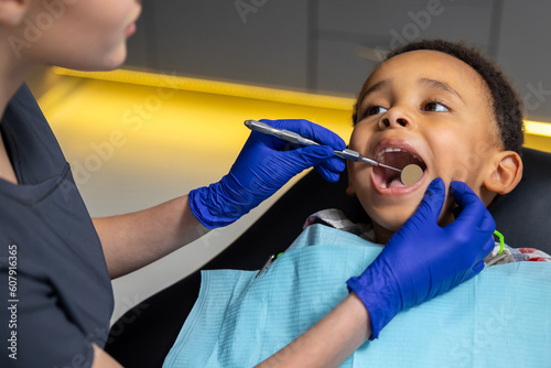 Female dentist working with dark-skinned boy