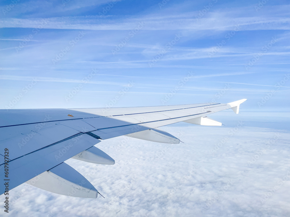 Fototapeta premium In Flight - Flying and traveling, view from airplane window of the wing with cloudscape and farm countryside below. Travel, Flight, airline, holiday, tourism concept