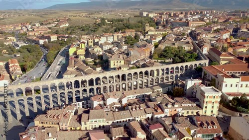 Cinematic aerial perspective of city center of Segovia. Aerial cinematic perspective of downtown Segovia. View of the ancient and famous aqueduct of Segovia, Drone backward ascending. Rooftops view