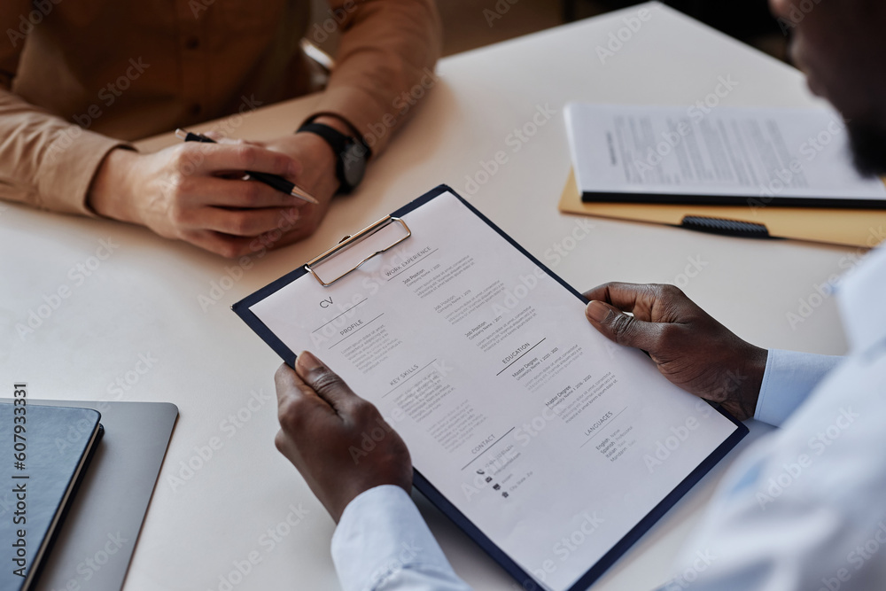 Close up of unrecognizable HR recruiter reading CV during job interview, copy space Close up of unrecognizable HR recruiter reading CV during job interview, copy space