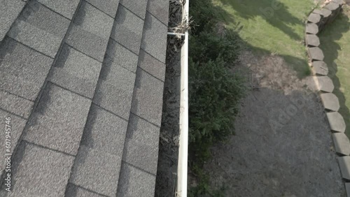 Dirty, metal gutters on a residential home are clogged with leaves and debris.