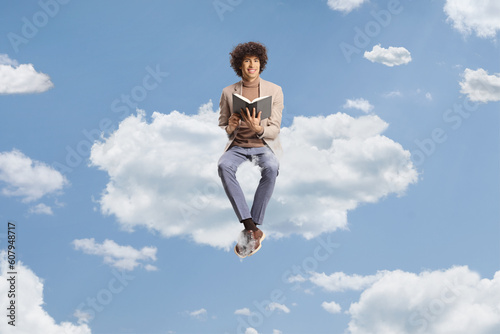 Young man with curly hair sitting on a cloud and holding a book