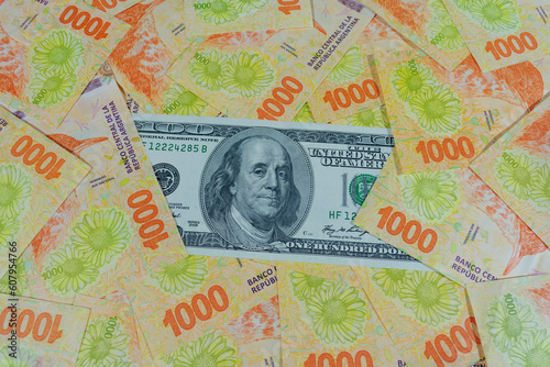 Obraz na płótnie 100 dollar bill surrounded by 1,000 Argentinian peso banknotes