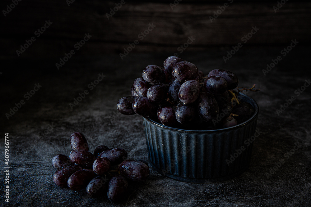 Obraz premium Bowl with black grapes on dark background 