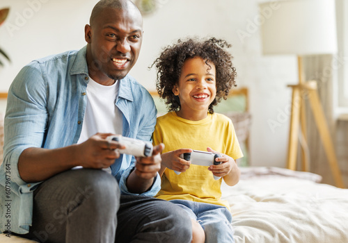Happy ethnic family father and son playing video game console at home