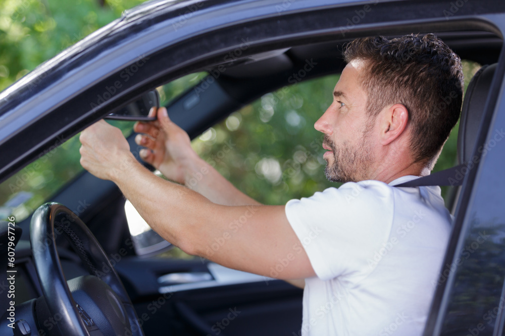 man adjusting mirror in car