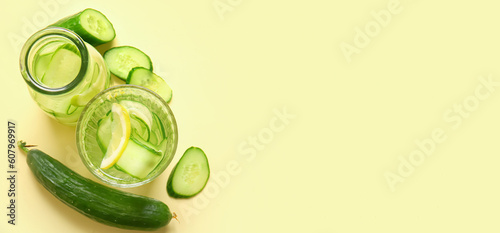 Bottle and glass of cucumber infused water on beige background with space for text