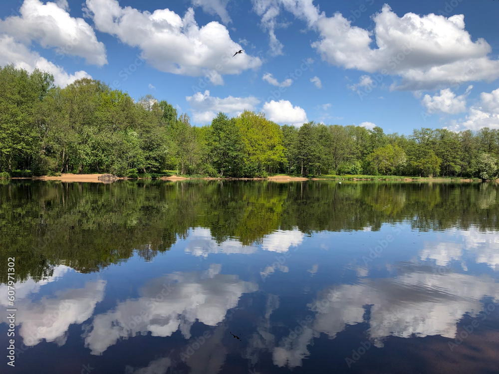Beautiful spring landscape by the river, mirror reflection of clouds in the water