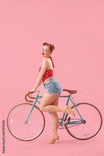 Young pin-up woman with bicycle on pink background © Pixel-Shot