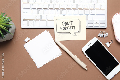 Reminder with stationery, mobile phone and computer keyboard on brown background