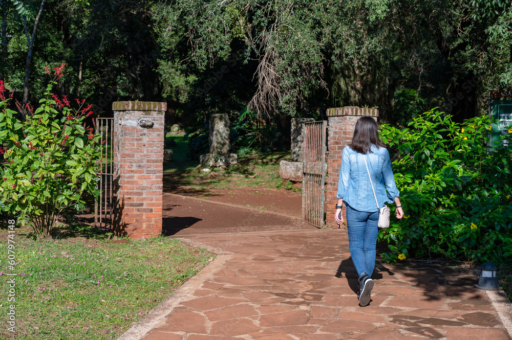 Fototapeta premium Woman tourist walking alone in jeans and loose hair walking through the ruins of San Ignacio Mini.
