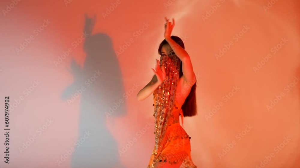 Young woman dancing oriental arabic dance. Pretty belly dancer in orange dress.