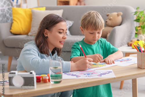 Nanny with little boy drawing at home photo