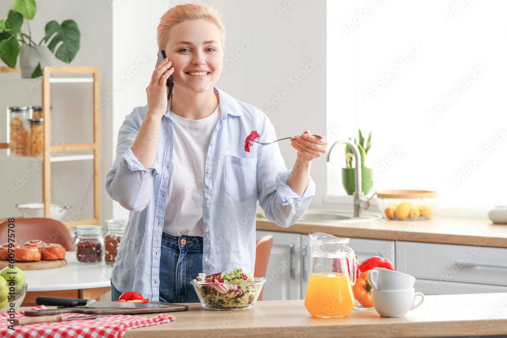 Young woman with vegetable salad talking by mobile phone in kitchen Young woman with vegetable salad talking by mobile phone in kitchen