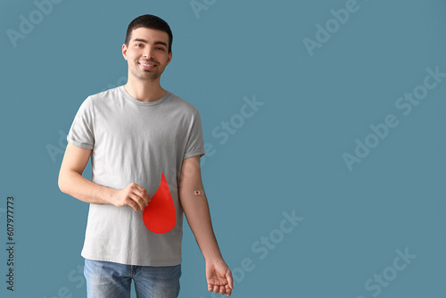 Photos Young blood donor with applied medical patch and paper drop on blue background