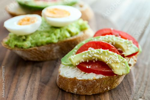 Board of tasty bruschettas with avocado on wooden background, closeup