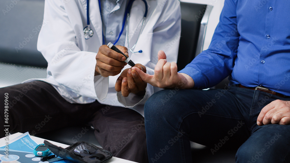 Fototapeta premium African american doctor doing medical test with diabetic man in hospital lobby, measuring insulin level and glucose in blood sample using glucometer. Seniorman having checkup visit appointment