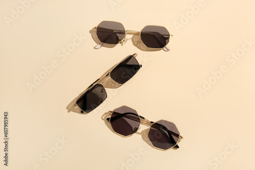 Different stylish sunglasses on beige background