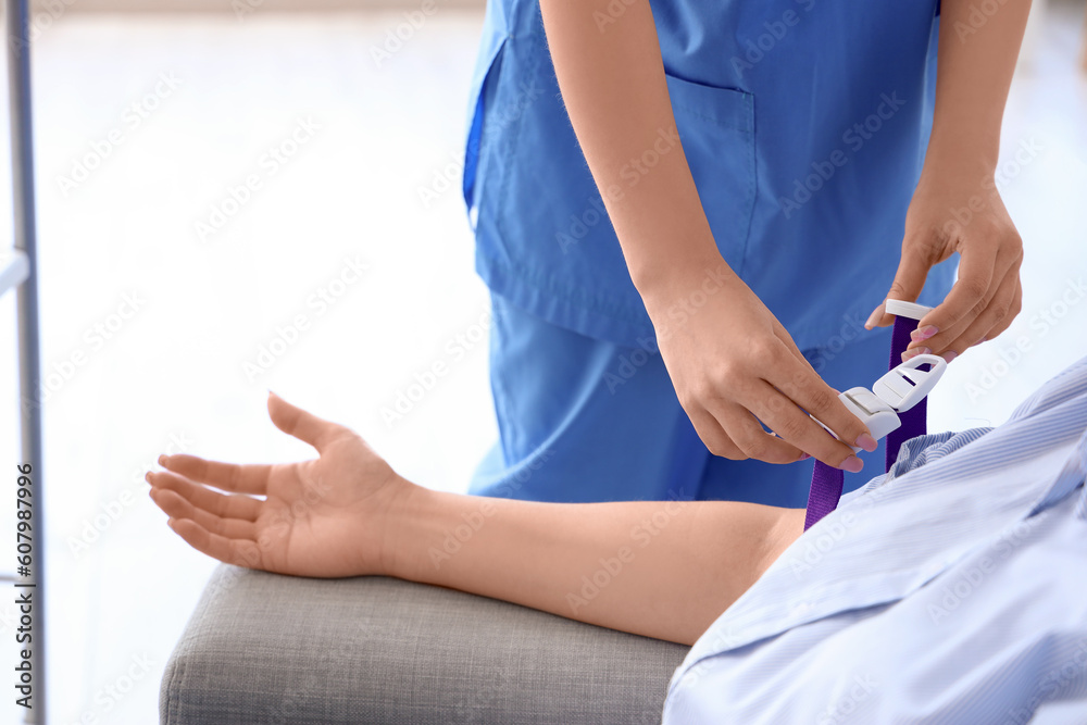 Female nurse preparing young donor for blood transfusion in clinic, closeup Female nurse preparing young donor for blood transfusion in clinic, closeup