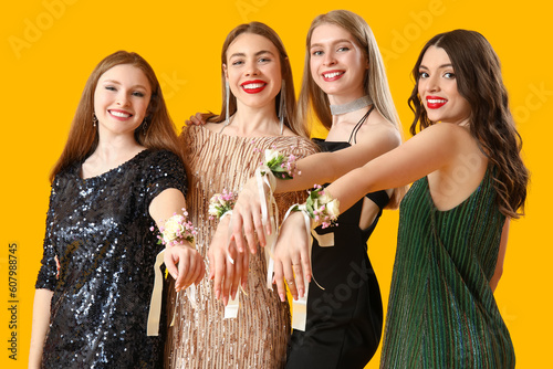 Young women dressed for prom with corsages on yellow background photo