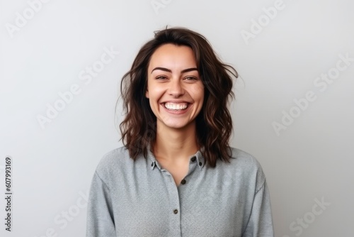 Portrait of a beautiful young woman laughing and looking at camera over gray background