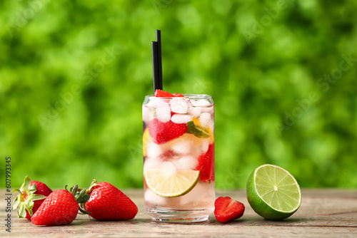 Glass of strawberry lemonade on wooden table outdoors