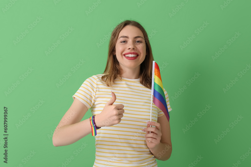 Young woman with LGBT flag showing thumb-up on green background Young woman with LGBT flag showing thumb-up on green background