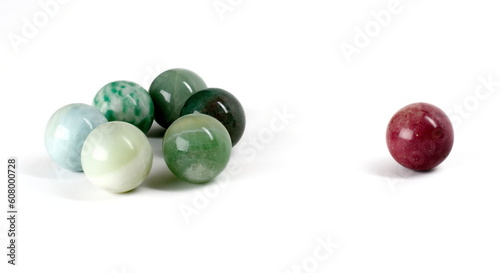 A lone marble excluded from a small group of  other, similarly colored marbles.