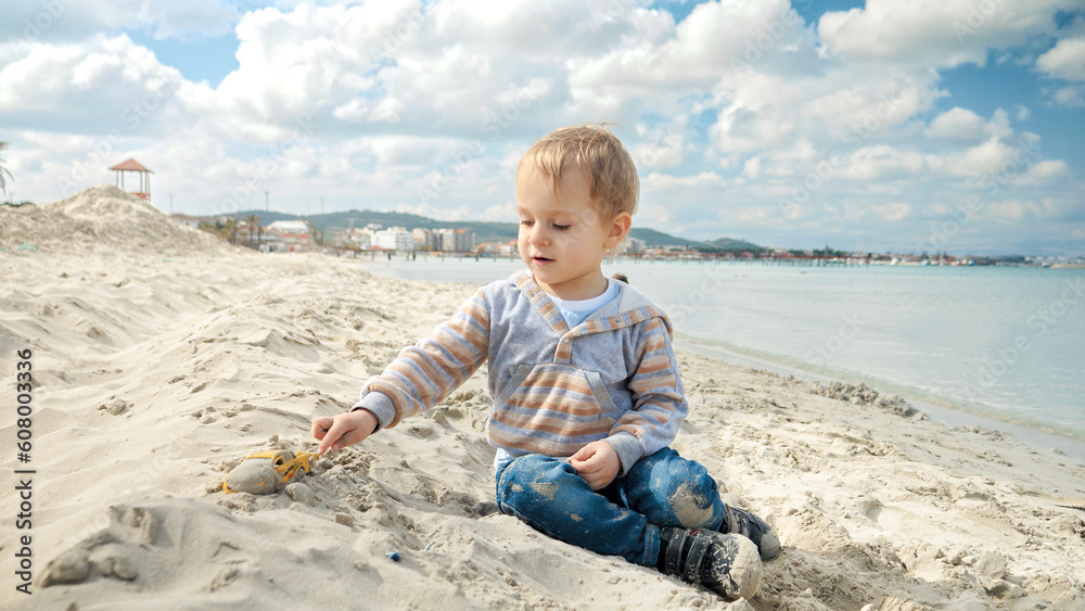 A little boy enjoys a relaxing day on the beach, playing with sand. Concept of tourism, travel, summer vacation A little boy enjoys a relaxing day on the beach, playing with sand. Concept of tourism, travel, summer vacation