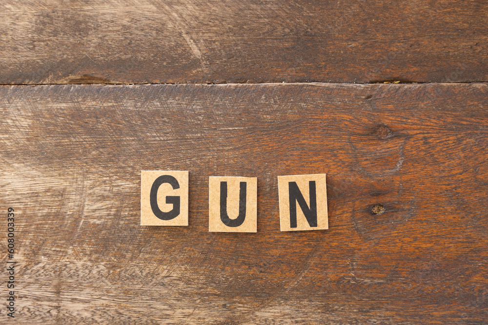 The word gun formed with wooden blocks on a rustic background.
