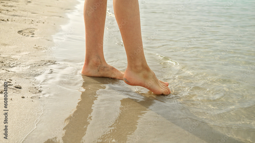 Closeup of little boy checking sea water temperature with his feet. Holiday, vacation, weekend at nature. Closeup of little boy checking sea water temperature with his feet. Holiday, vacation, weekend at nature.