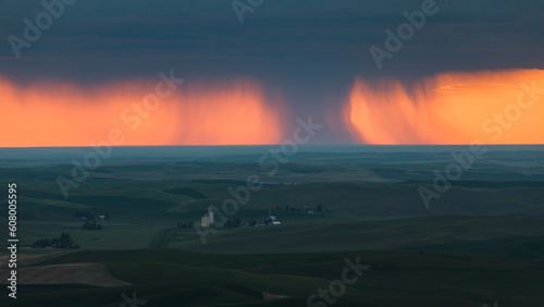 Ominous view across the Palouse in Eastern Washington of rain shaft at sunset over spring fields