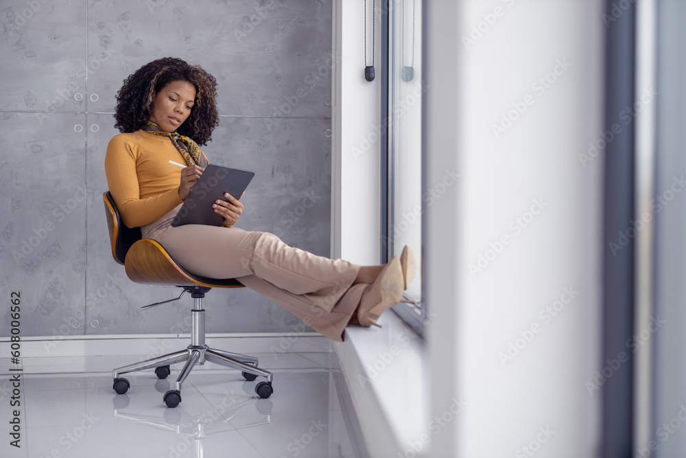 Serious african-american businesswoman using digital tablet in office Serious african-american businesswoman using digital tablet in office