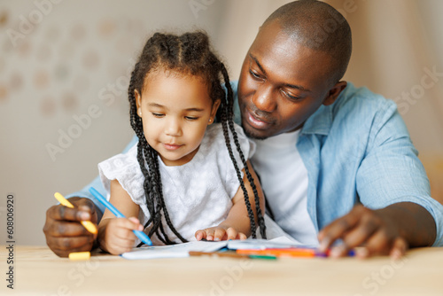 Teaching children. Happy ethnic family father painting together with cute daughter