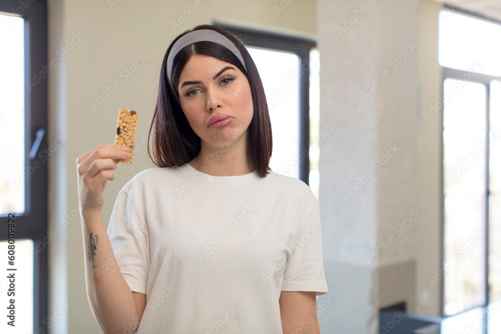 pretty young woman feeling sad and whiney with an unhappy look and crying. fitness cereal bar concept