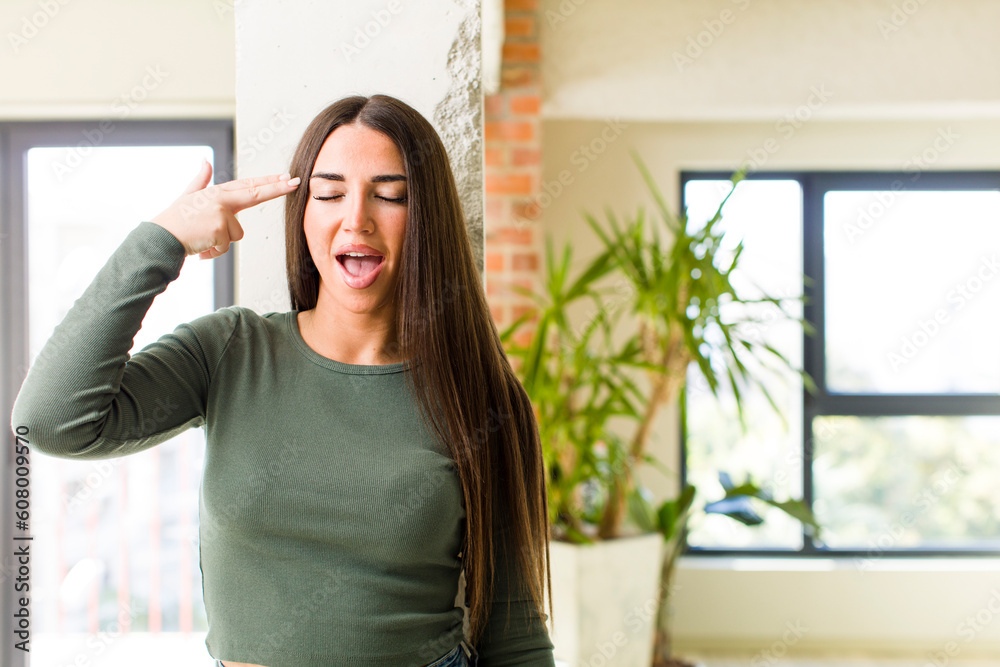 young adult pretty woman looking unhappy and stressed, suicide gesture making gun sign with hand, pointing to head young adult pretty woman looking unhappy and stressed, suicide gesture making gun sign with hand, pointing to head