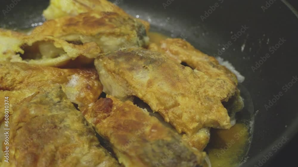 Fried fish in a frying pan in oil with bubbles, moving sideways on a slider Fried fish in a frying pan in oil with bubbles, moving sideways on a slider