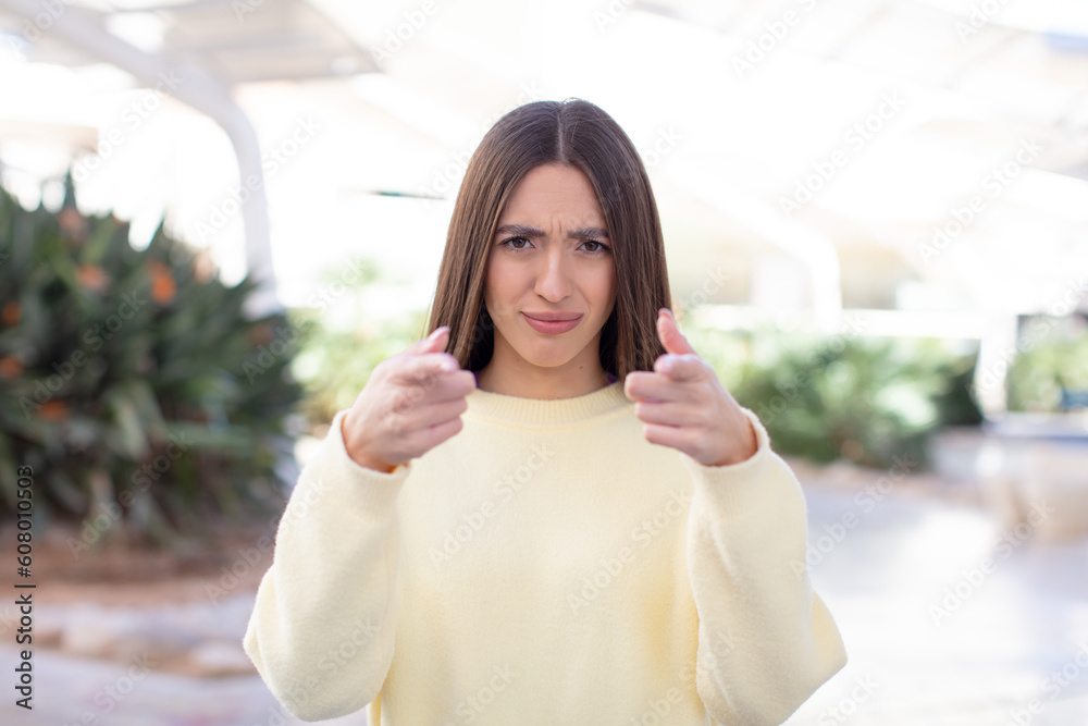 young pretty woman pointing forward at camera with both fingers and angry expression, telling you to do your duty